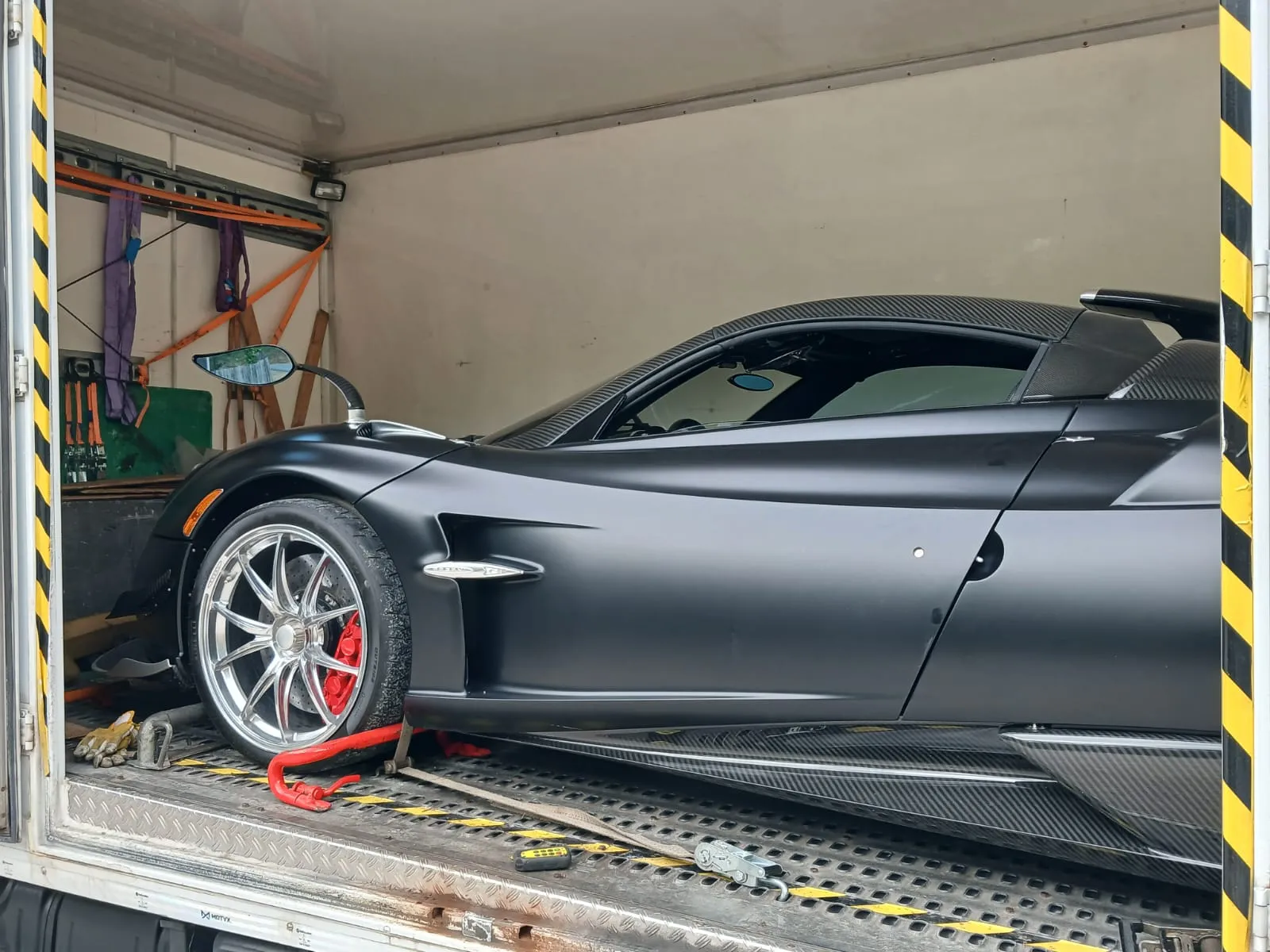 Pagani Huayra nera di profilo dentro il furgonato Lory con le porte laterali aperte